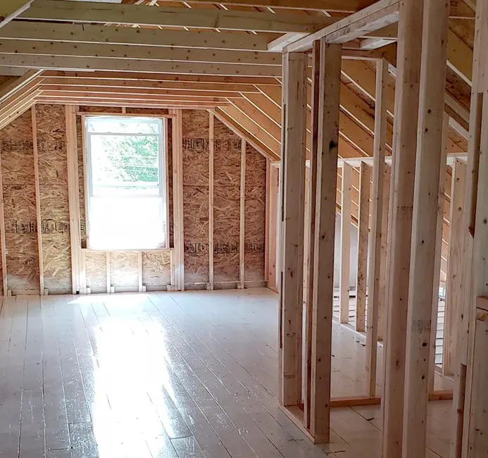 Unfinished attic space with exposed wooden framing and a single window letting in natural light.