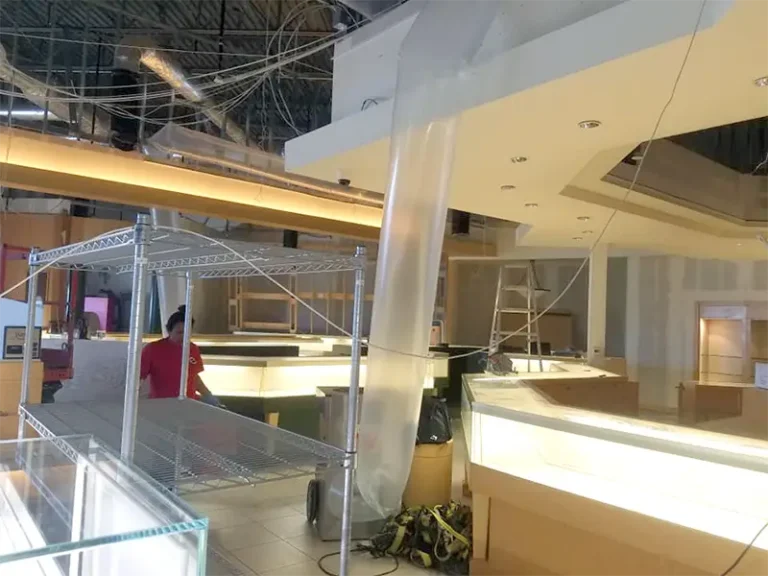 Interior of a store under construction with metal shelving, display cases, and a ladder.