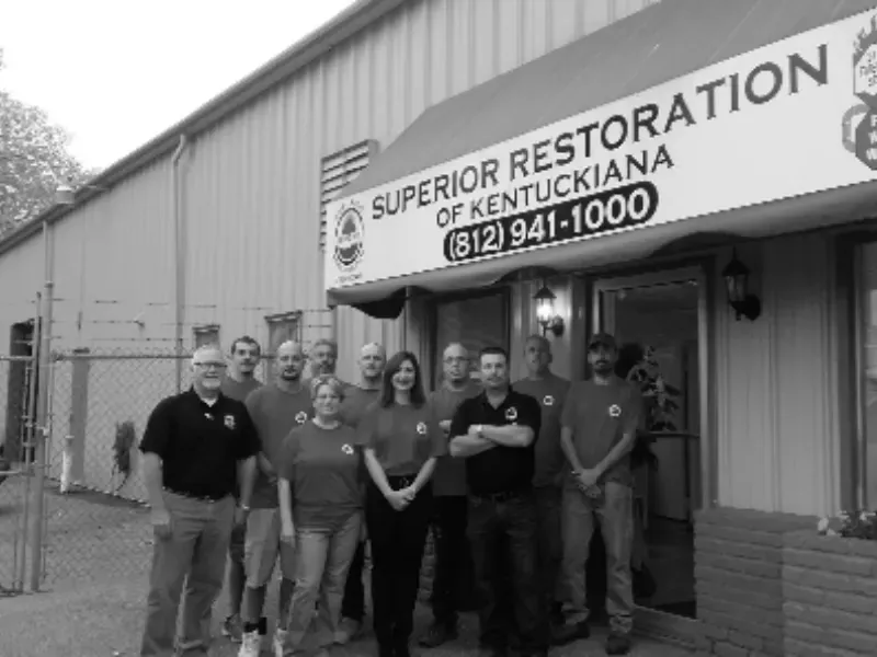 Group of people standing outside a building with a "Superior Restoration of Kentuckiana" sign above the entrance.